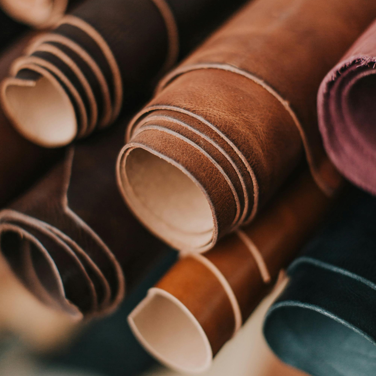 Rolls of leather in various colors arranged on a dark surface